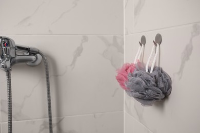 Photo of Shower puffs hanging near faucet in bathroom, space for text