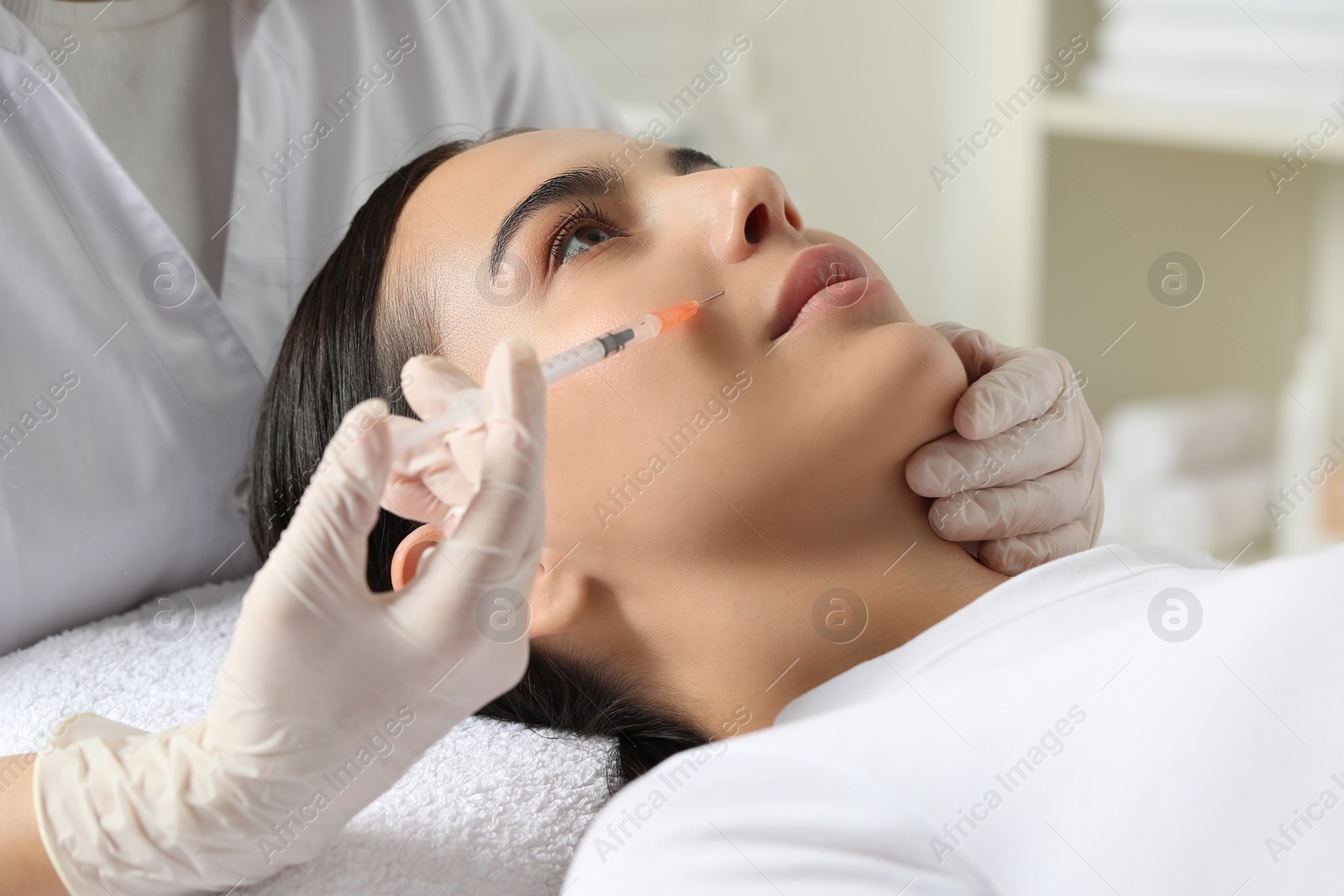 Photo of Doctor giving facial injection to young woman in clinic. Cosmetic surgery