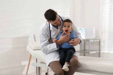 Pediatrician examining cute little boy at hospital