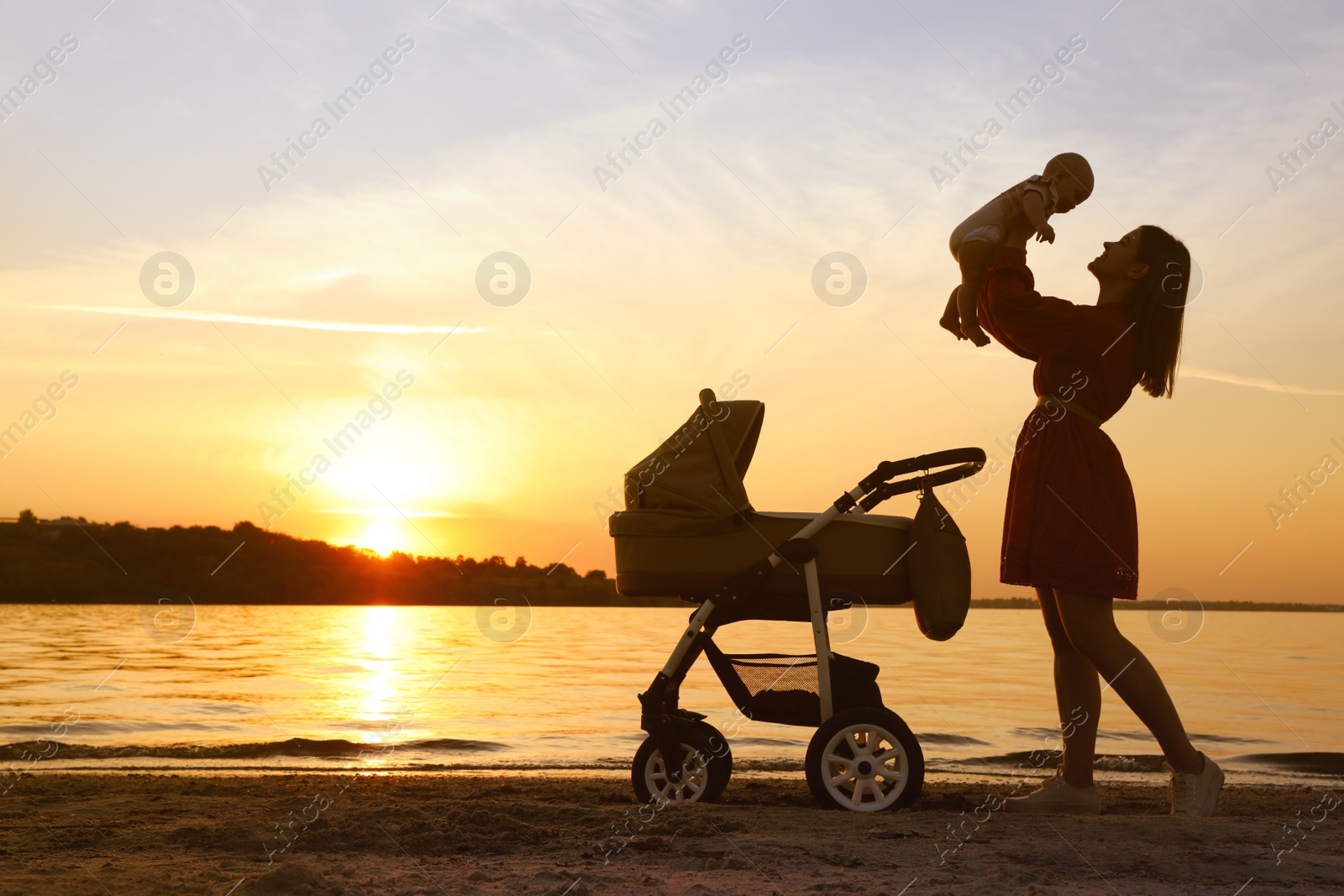 Photo of Happy mother with baby near river at sunset