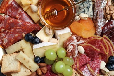 Photo of Different appetizers with delicious honey as background, top view