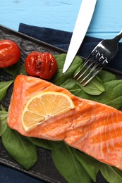 Photo of Tasty grilled salmon with tomatoes, spinach and lemon served on table, top view