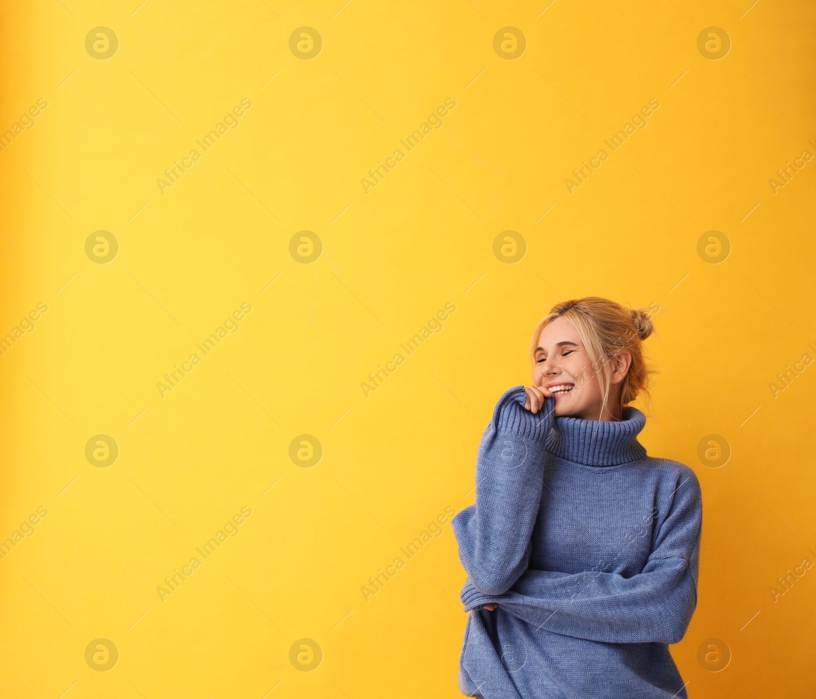 Photo of Happy woman in stylish sweater on yellow background. Space for text