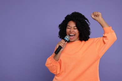 Beautiful woman with microphone singing on violet background, space for text