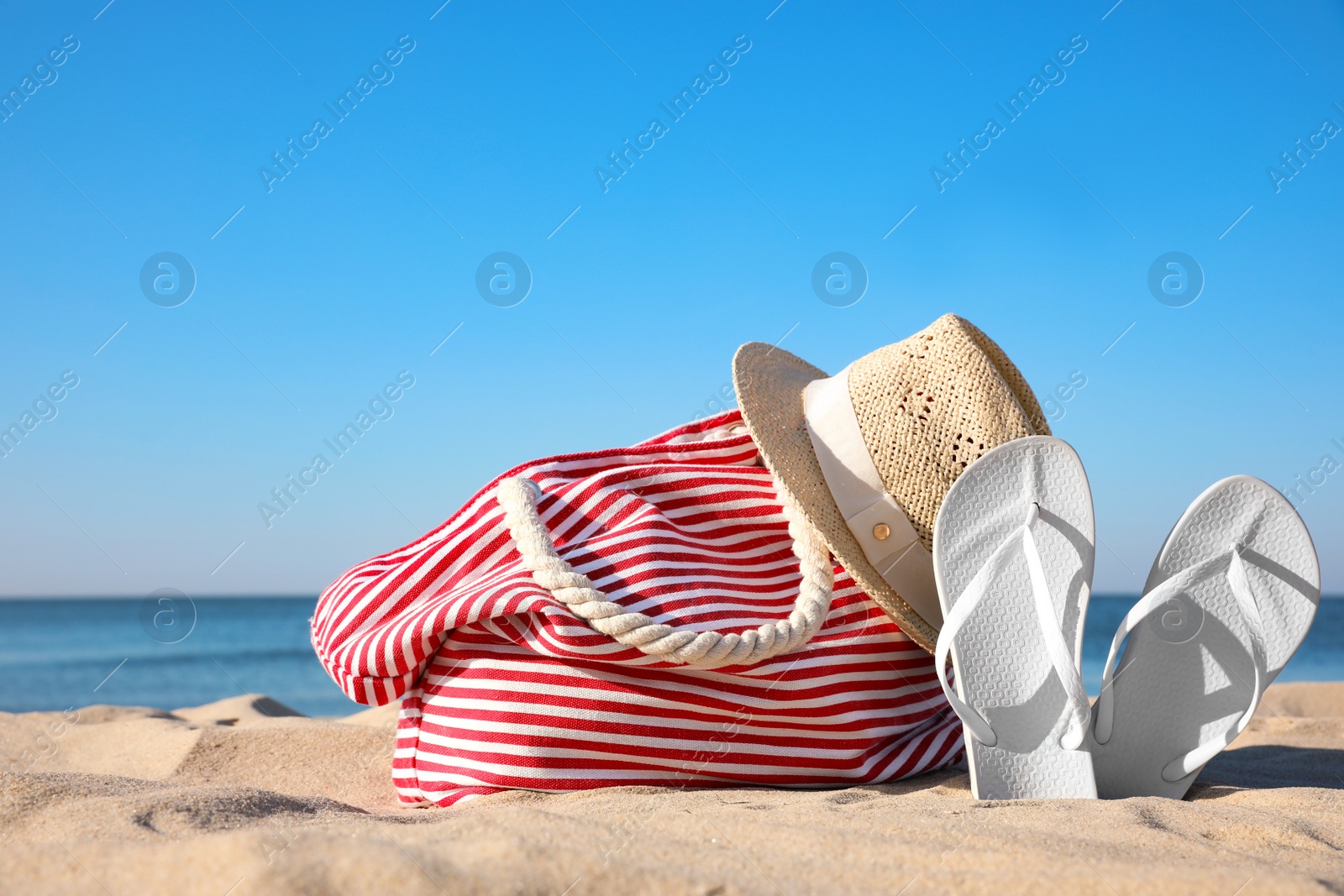 Photo of Set with stylish beach accessories on sand near sea