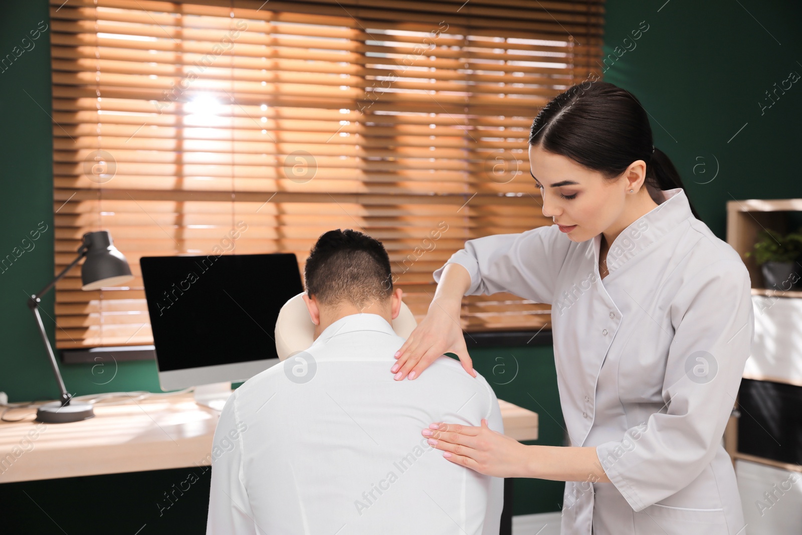 Photo of Man receiving massage in modern chair indoors