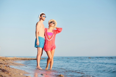Photo of Happy young couple walking together on beach. Space for text