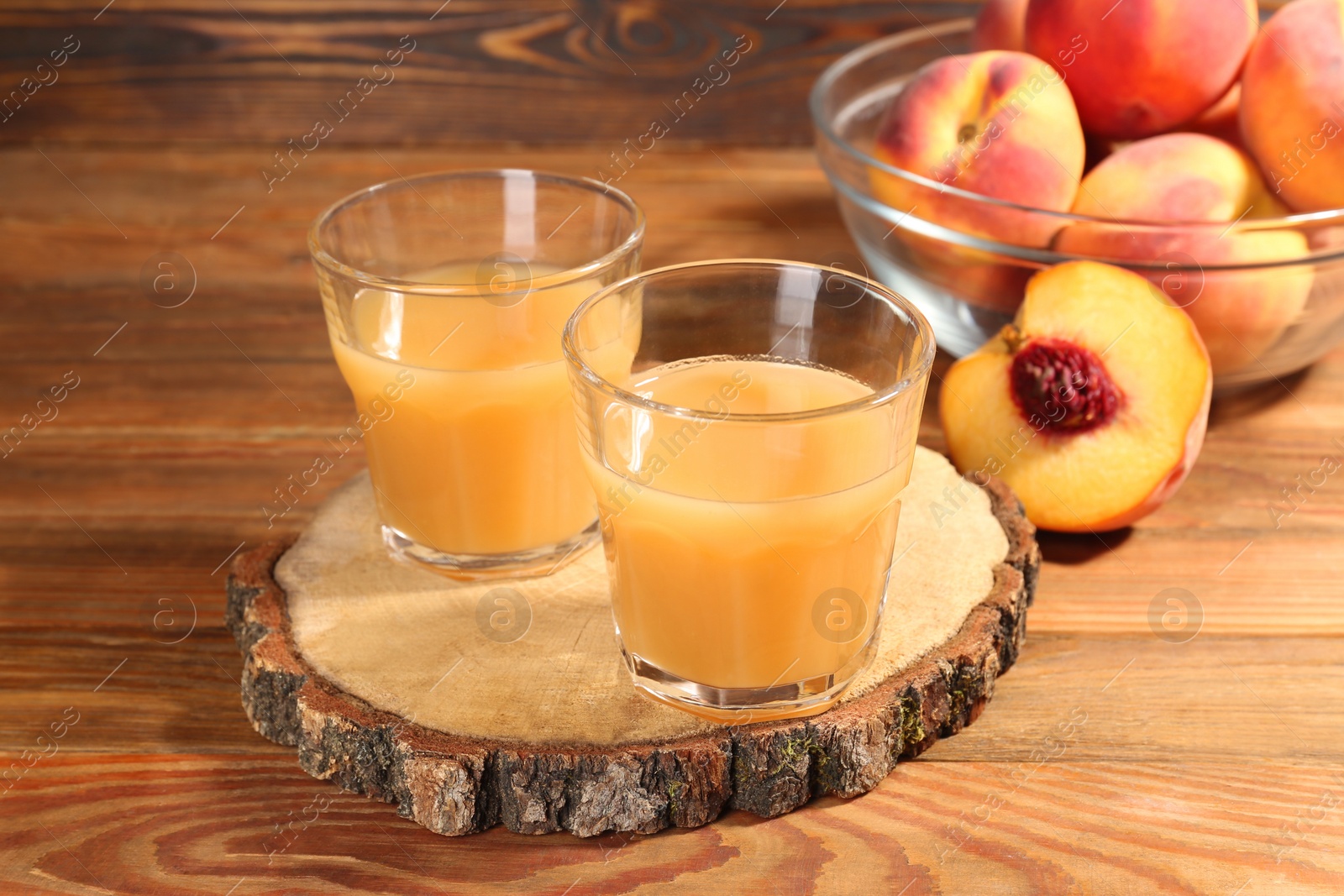 Photo of Glasses of delicious peach juice and fresh fruits on wooden table
