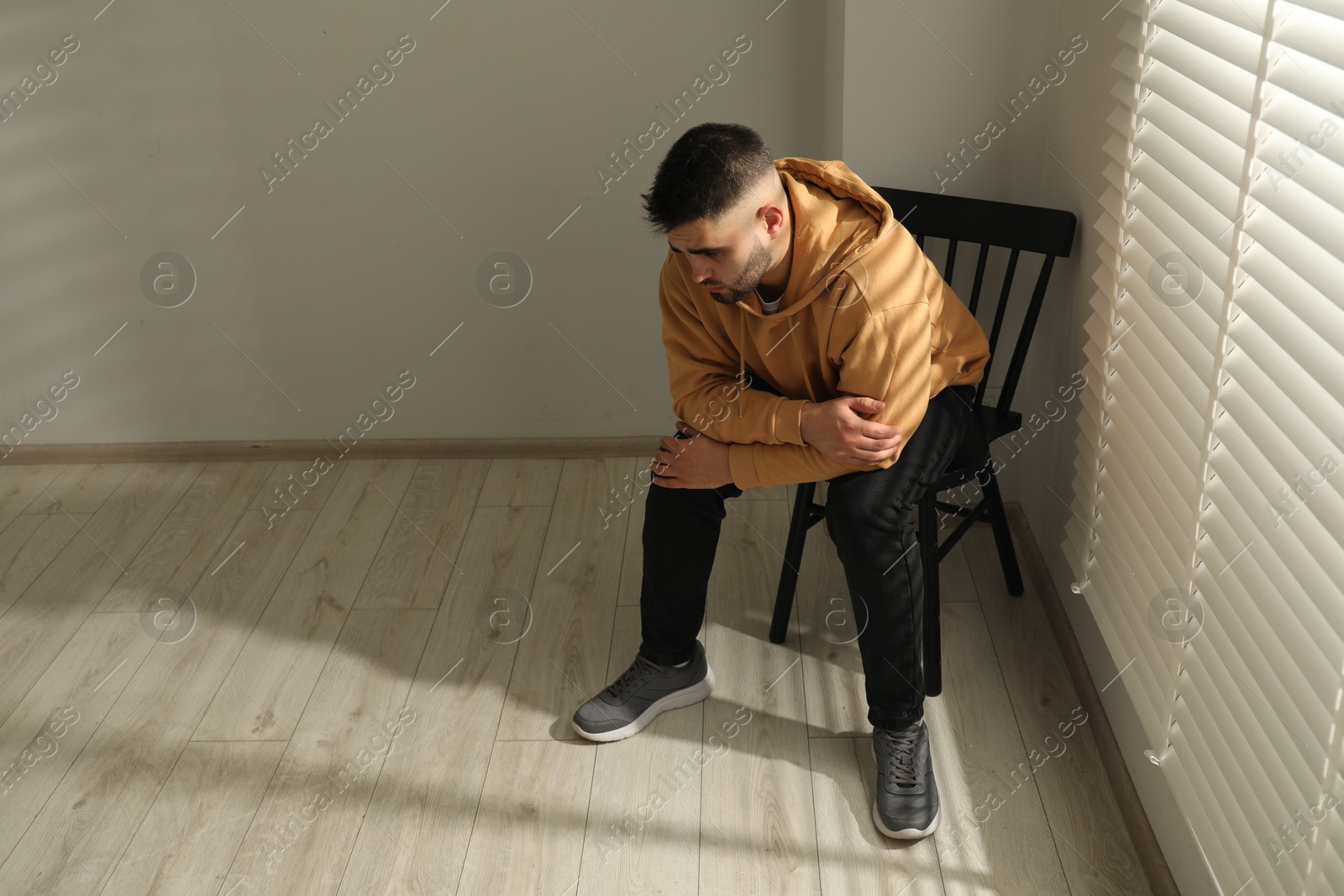 Photo of Sad man sitting on chair near window. Space for text