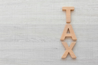 Photo of Word TAX on wooden background, top view