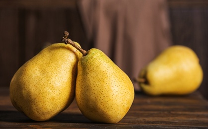 Photo of Fresh ripe pears on wooden table against blurred background