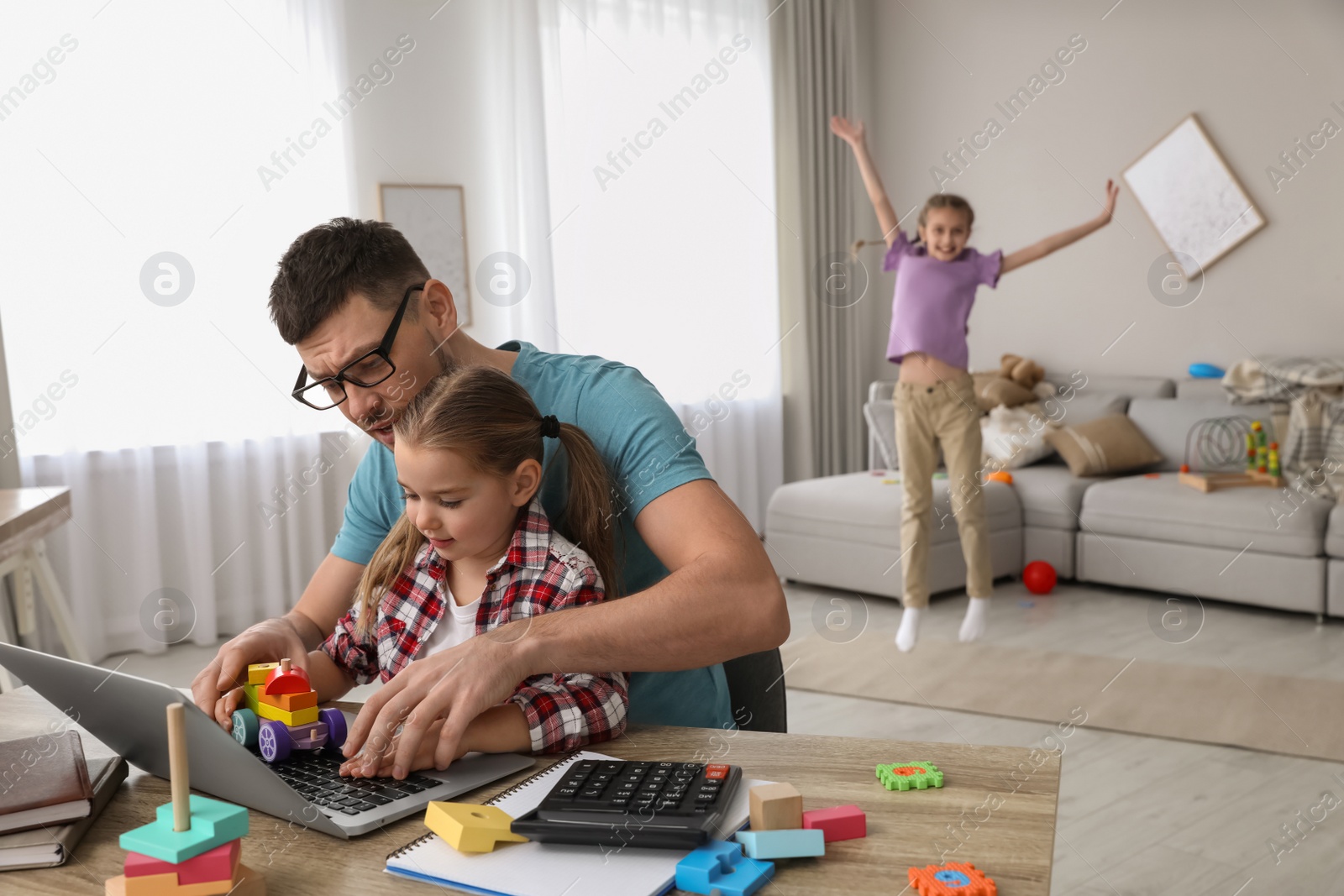 Photo of Children disturbing stressed man in living room. Working from home during quarantine