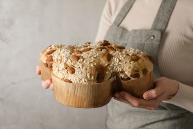 Photo of Woman with delicious Italian Easter dove cake (traditional Colomba di Pasqua) near grey wall, closeup