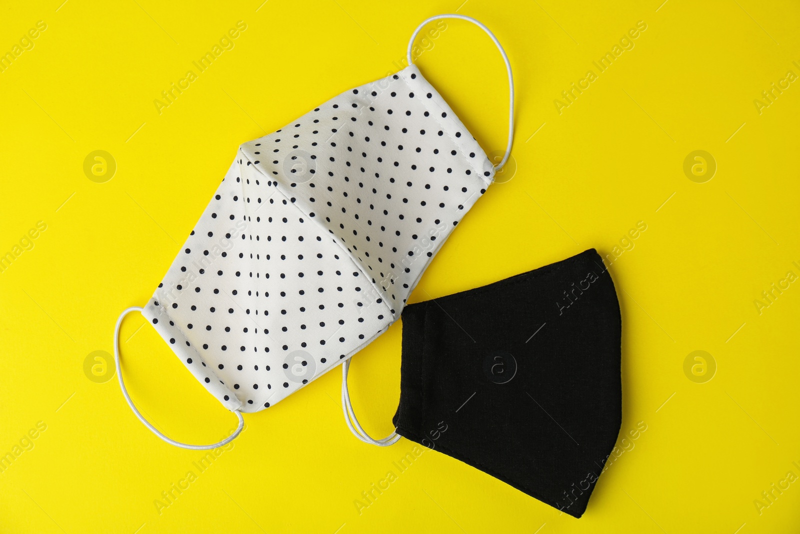 Photo of Homemade protective face masks on yellow background, flat lay