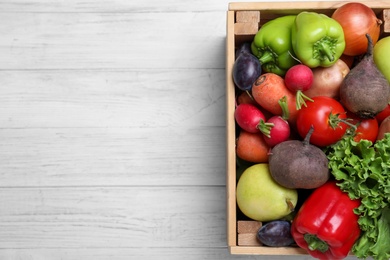 Photo of Crate of harvested vegetables on white wooden table, top view. Space for text