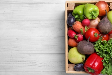 Crate of harvested vegetables on white wooden table, top view. Space for text