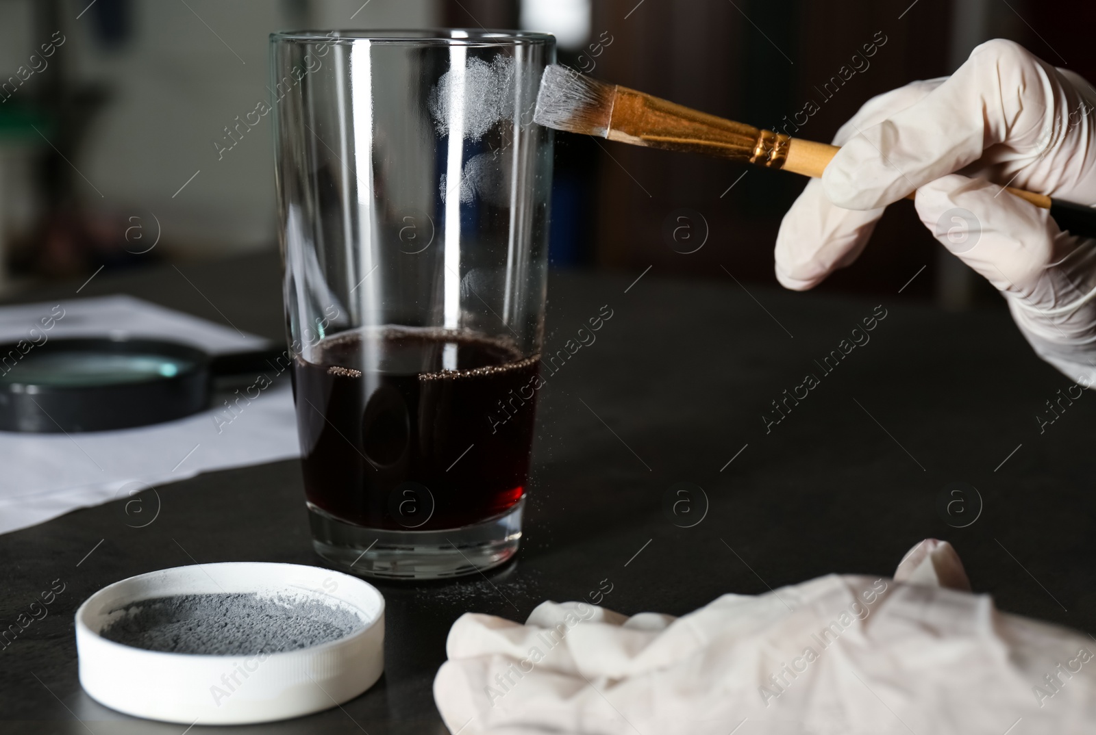 Photo of Detective taking fingerprints with brush from glass, closeup