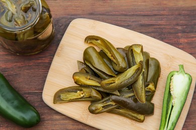 Photo of Fresh and pickled green jalapeno peppers on wooden table, above view