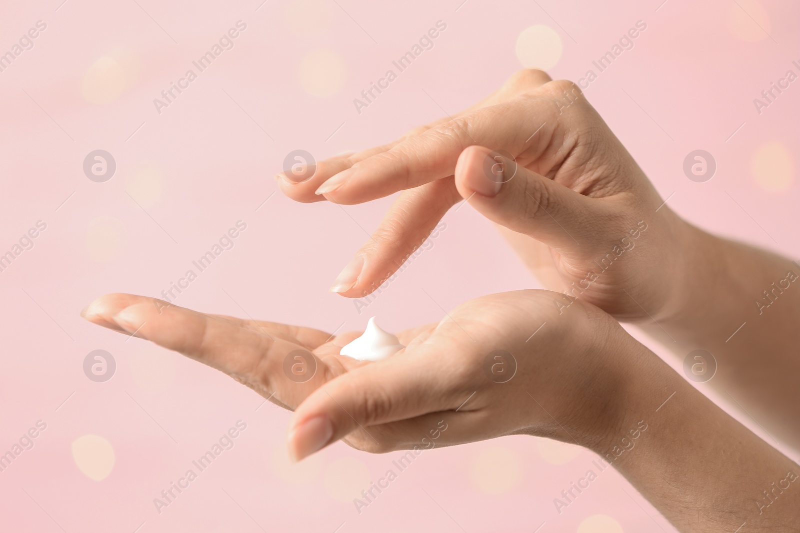 Photo of Woman applying hand cream on blurred background, closeup