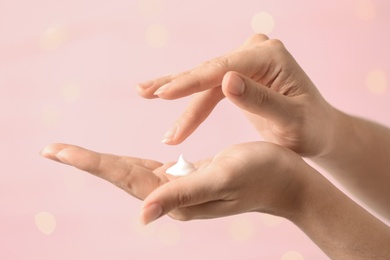 Photo of Woman applying hand cream on blurred background, closeup