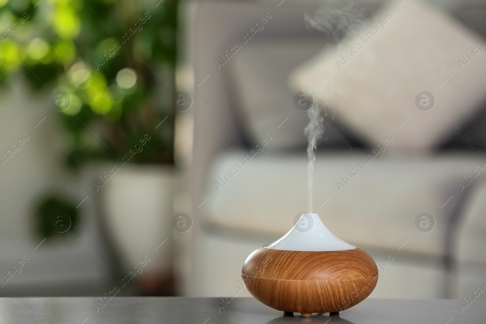 Photo of Aroma oil diffuser lamp on table against blurred background