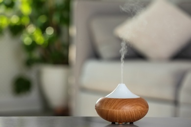 Aroma oil diffuser lamp on table against blurred background