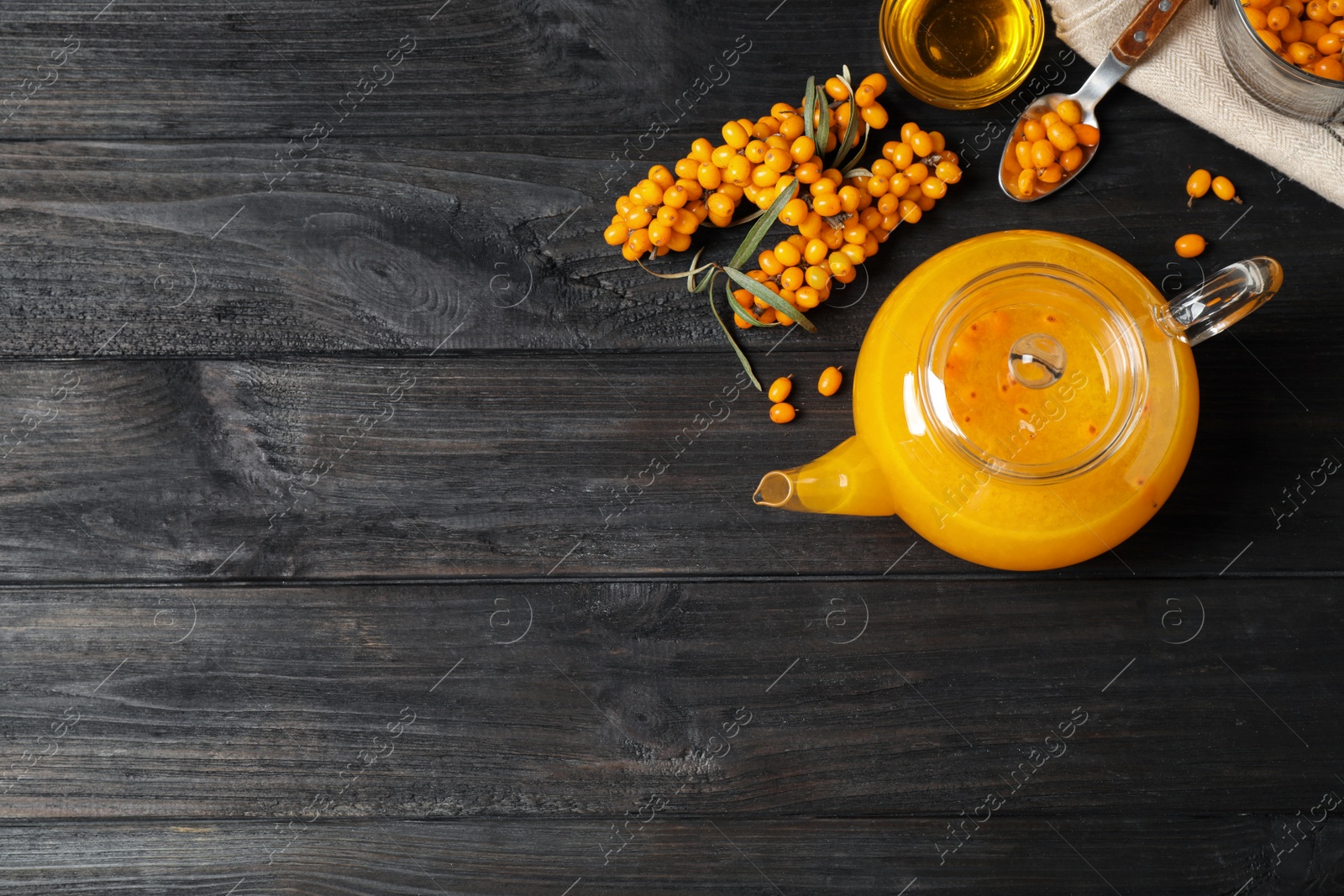 Photo of Delicious sea buckthorn tea and fresh berries on black wooden table, flat lay. Space for text