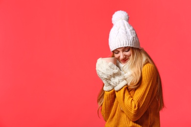 Photo of Portrait of emotional young woman in stylish clothes with cup on color background, space for text. Winter atmosphere