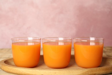 Photo of Glasses of freshly made carrot juice on wooden plate