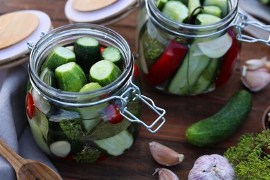 Photo of Glass jars with fresh cucumbers and other ingredients on wooden table. closeup. Canning vegetables