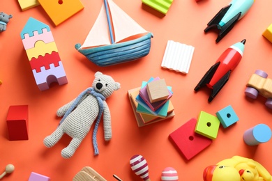 Different toys on orange background, flat lay