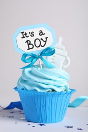Photo of Beautifully decorated baby shower cupcake for boy with cream and topper on light background