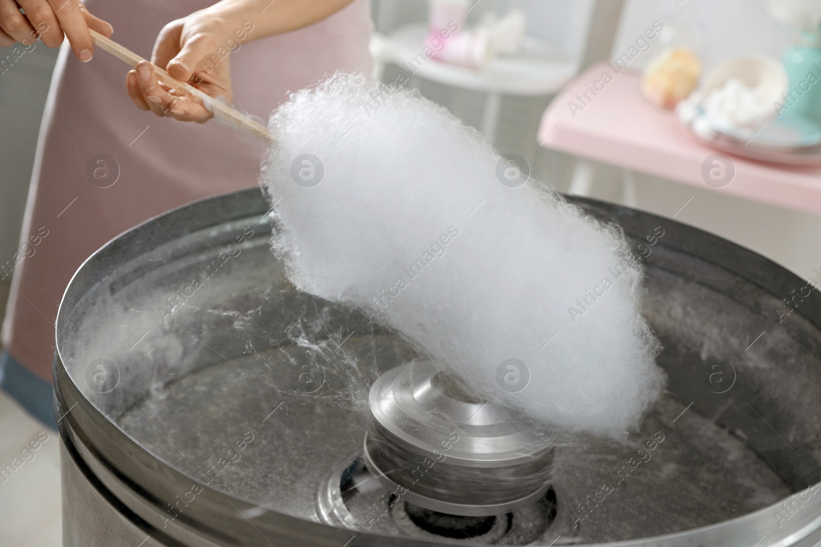 Photo of Woman making cotton candy using modern machine indoors, closeup