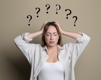Image of Amnesia. Confused young woman and question marks on beige background