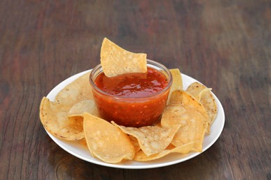Tasty salsa sauce and tortilla chips on wooden table, closeup
