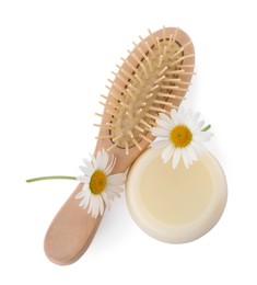 Photo of Solid shampoo bar, hairbrush and chamomiles on white background, top view. Hair care