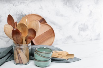 Photo of Different dishware and utensils on white marble table against textured wall. Space for text