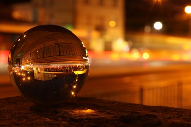 Photo of Beautiful city street, overturned reflection. Crystal ball at night. Space for text