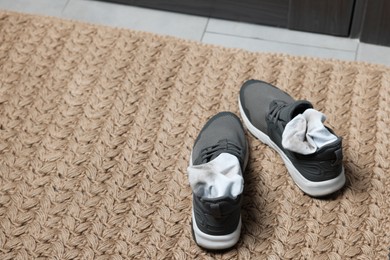 Photo of Sneakers with dirty socks on woven mat indoors, closeup. Space for text