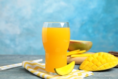 Photo of Glass of fresh mango juice and tasty fruits on wooden table