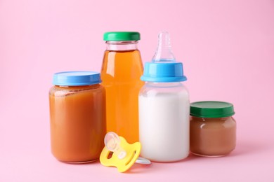 Healthy baby food, juice, milk and pacifier on pink background