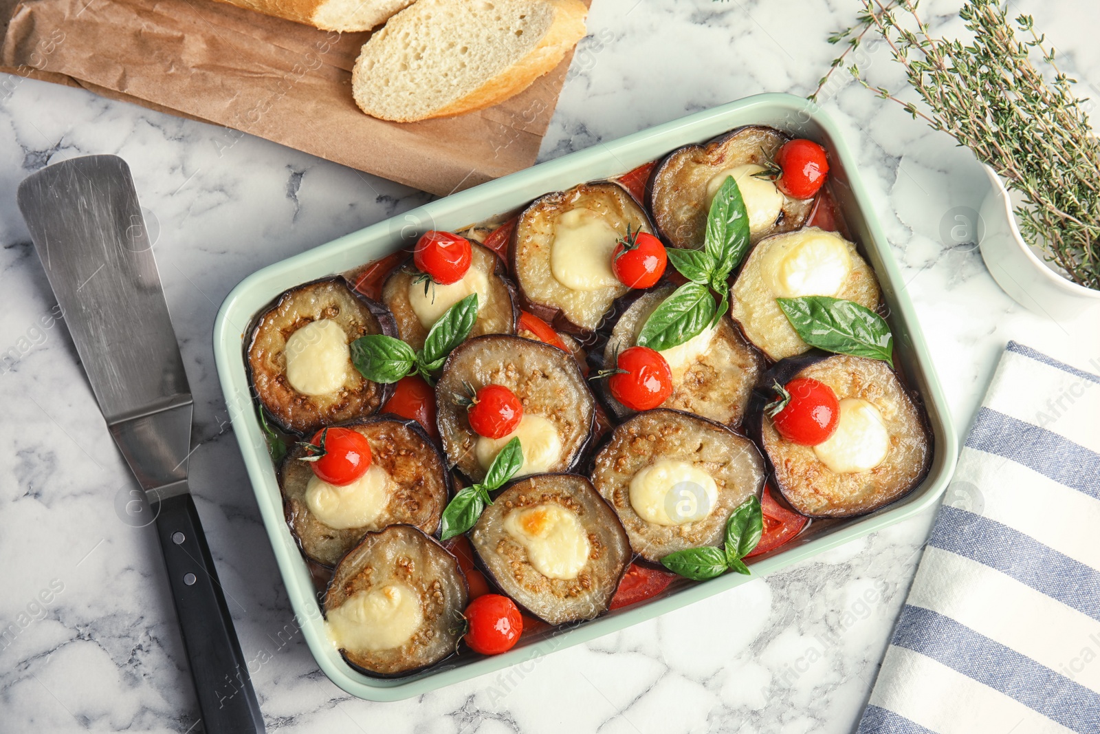 Photo of Flat lay composition with baked eggplant, tomatoes and basil in dishware  on marble table