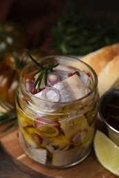 Photo of Tasty marinated fish with onion and rosemary in jar on wooden table, closeup