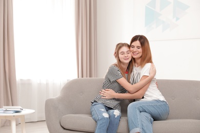 Happy mother hugging her teenager daughter at home