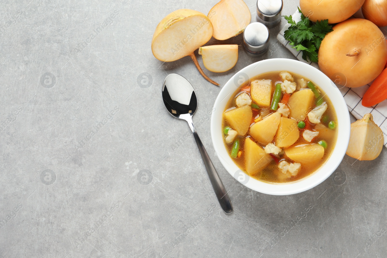 Photo of Bowl of delicious turnip soup served on light grey table, flat lay. Space for text