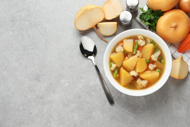 Bowl of delicious turnip soup served on light grey table, flat lay. Space for text