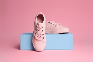 Photo of Pair of stylish canvas shoes and box on pink background