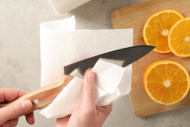 Photo of Woman wiping knife with paper towel at table, top view