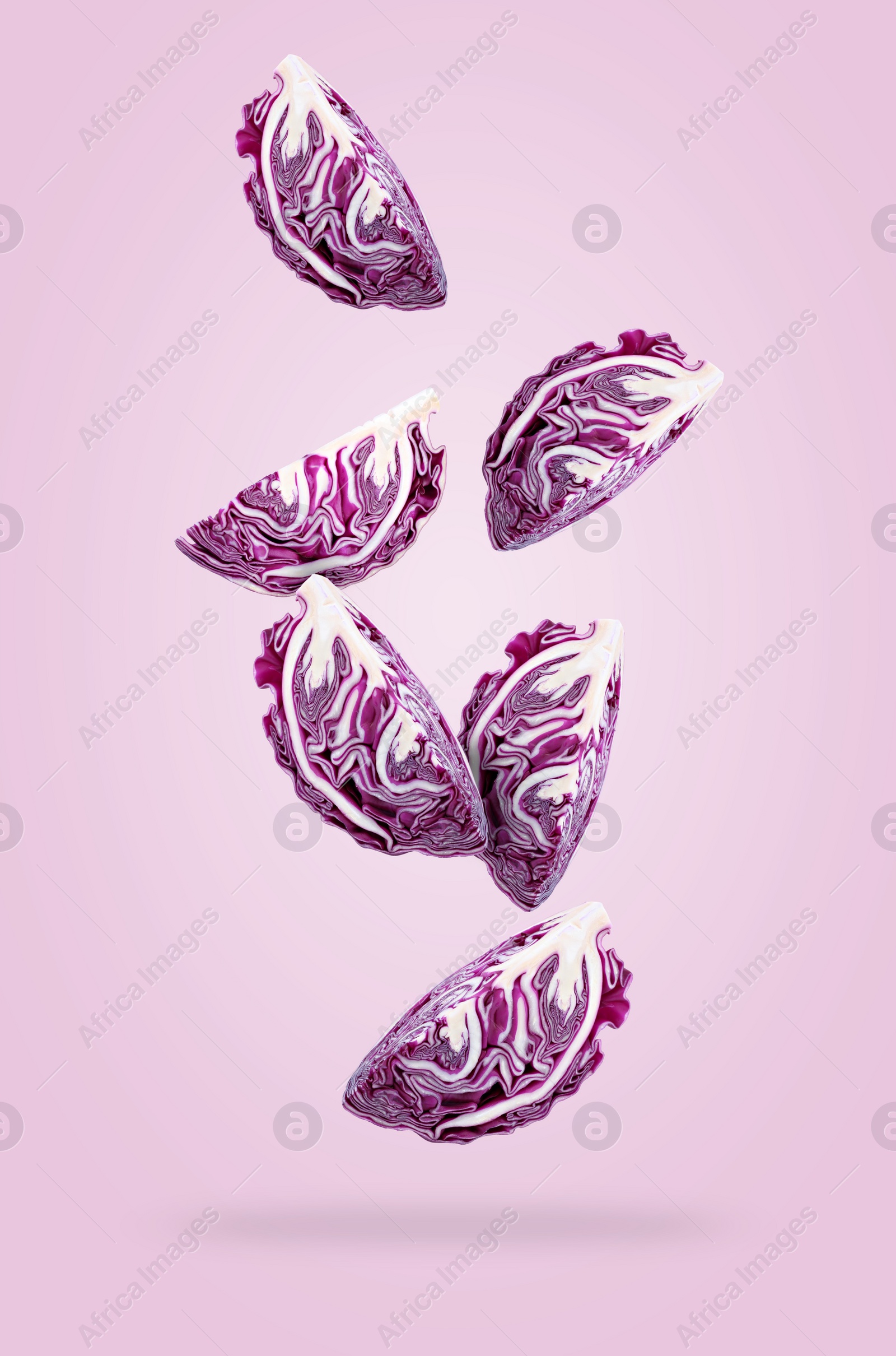 Image of Cut fresh red cabbages falling on lilac background