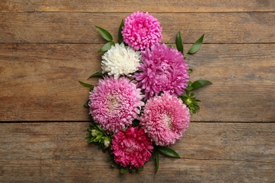 Photo of Beautiful asters on wooden background, flat lay. Autumn flowers